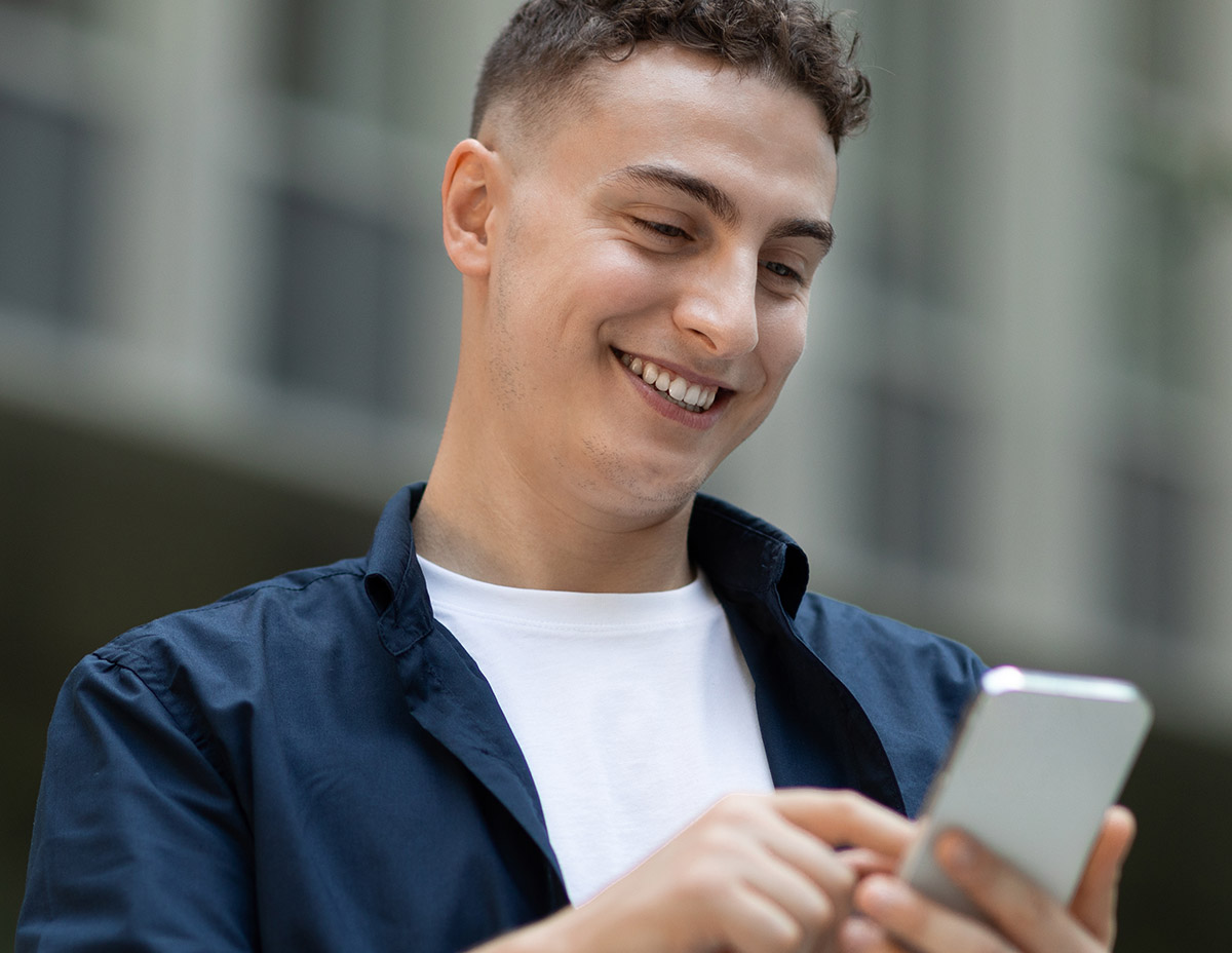 Young man smiling using his mobile phone.